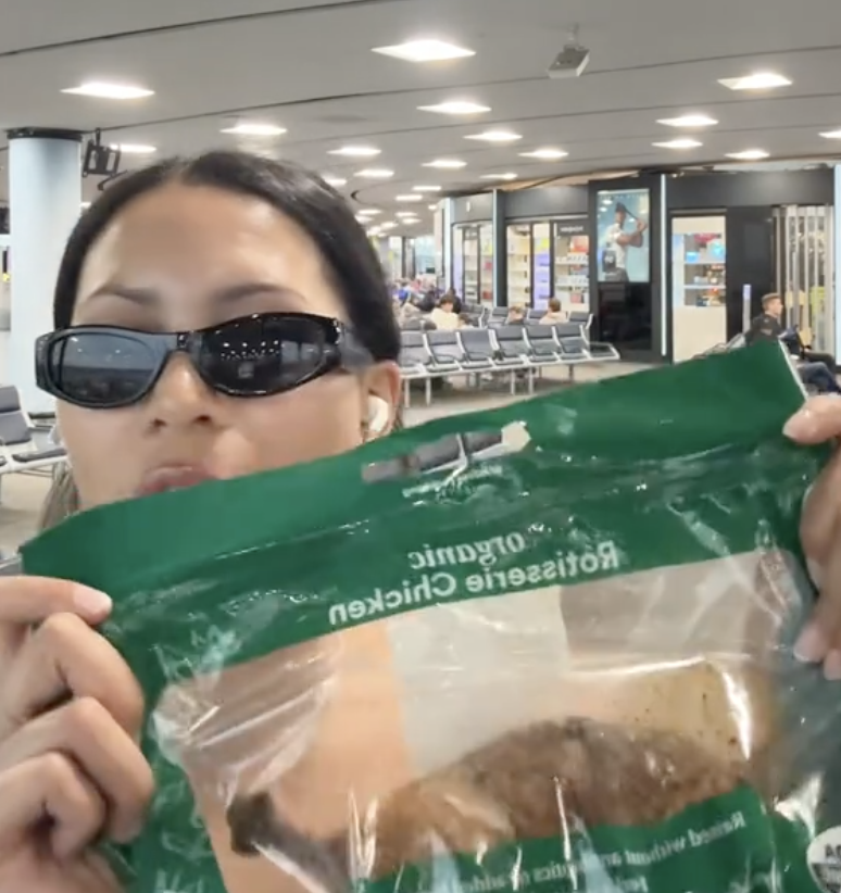 woman holding a rotisserie chicken